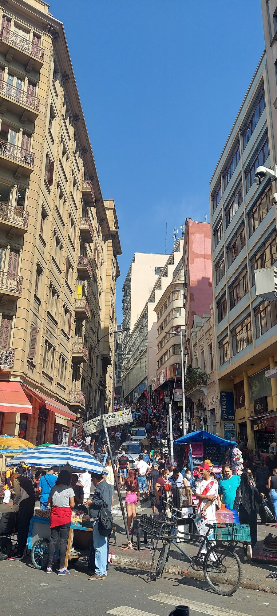 Rua do entorno da 25 de Março cheia de compradores e barracas