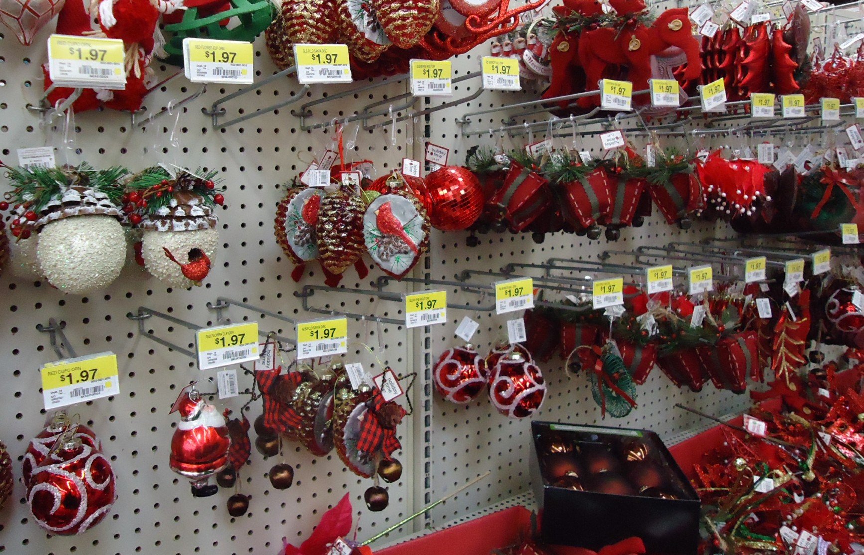 Prateleira de loja com enfeites de Natal vermelhos e brancos pendurados em ganchos