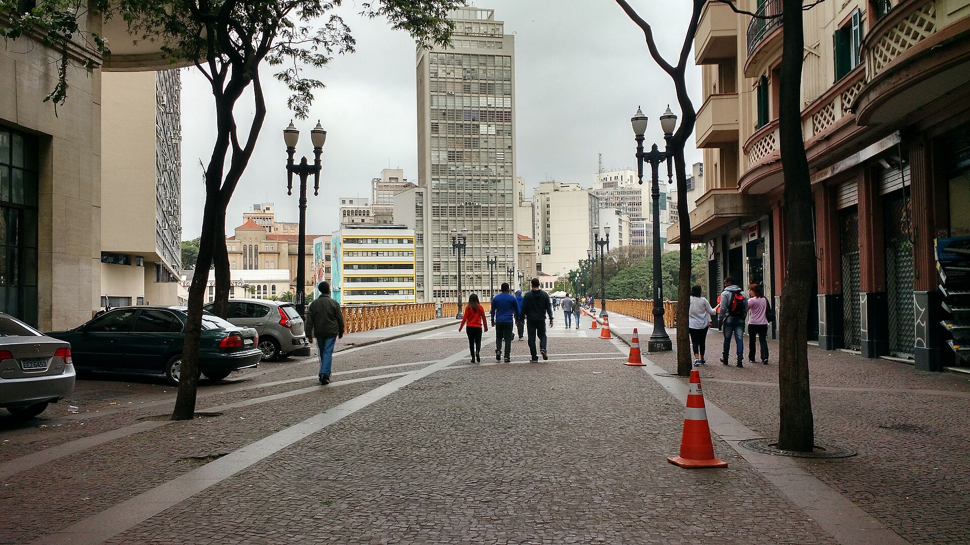 Pedestres caminham pelo calçamento de pedra na entrada do Viaduto Santa Ifigênia, a partir do Largo São Bento