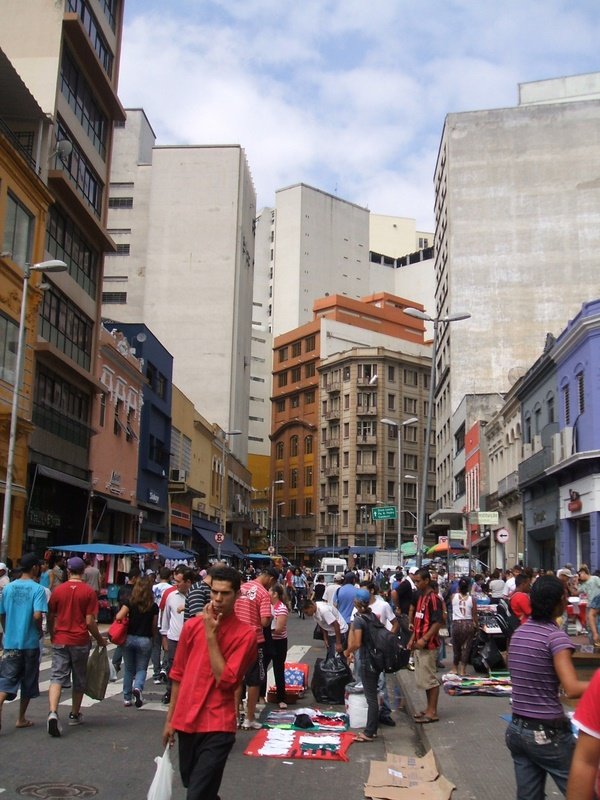 Rua 25 de Março com lojas e pedestres entre as fachadas